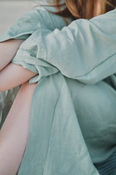 Artistic close-up of a person wrapped in a soft green fabric, evoking elegance and serenity.