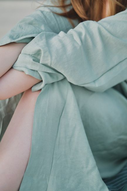 Artistic close-up of a person wrapped in a soft green fabric, evoking elegance and serenity.