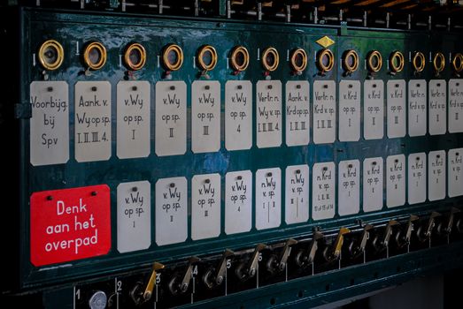 Close-up of a vintage Dutch mechanical control panel with labels.