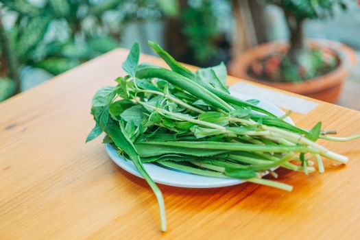 Close-up of fresh green herbs on a ceramic plate, perfect for healthy cooking.