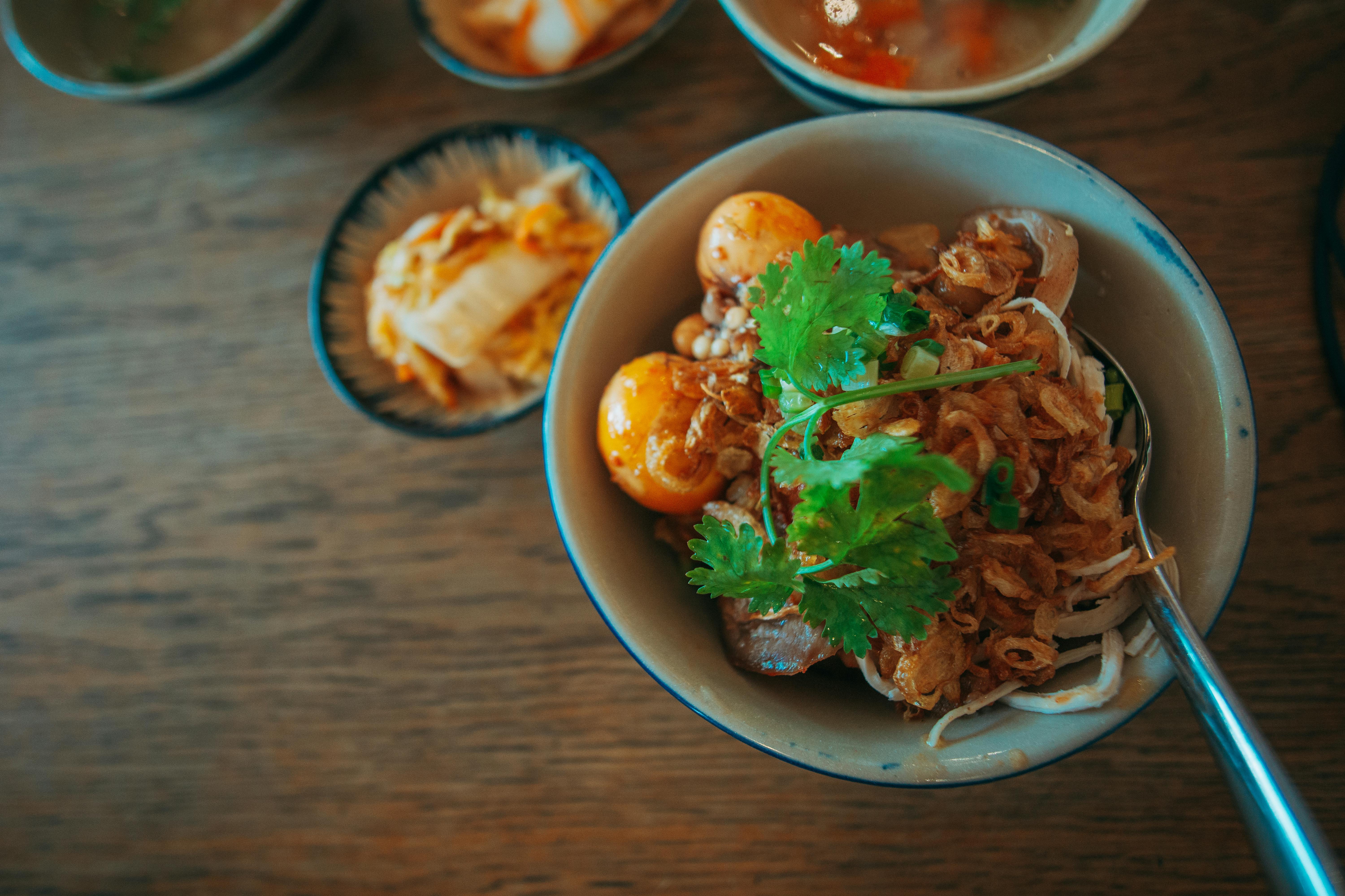 Top view of a flavorful Asian noodle bowl with egg and cilantro, perfectly garnished for a delightful meal.