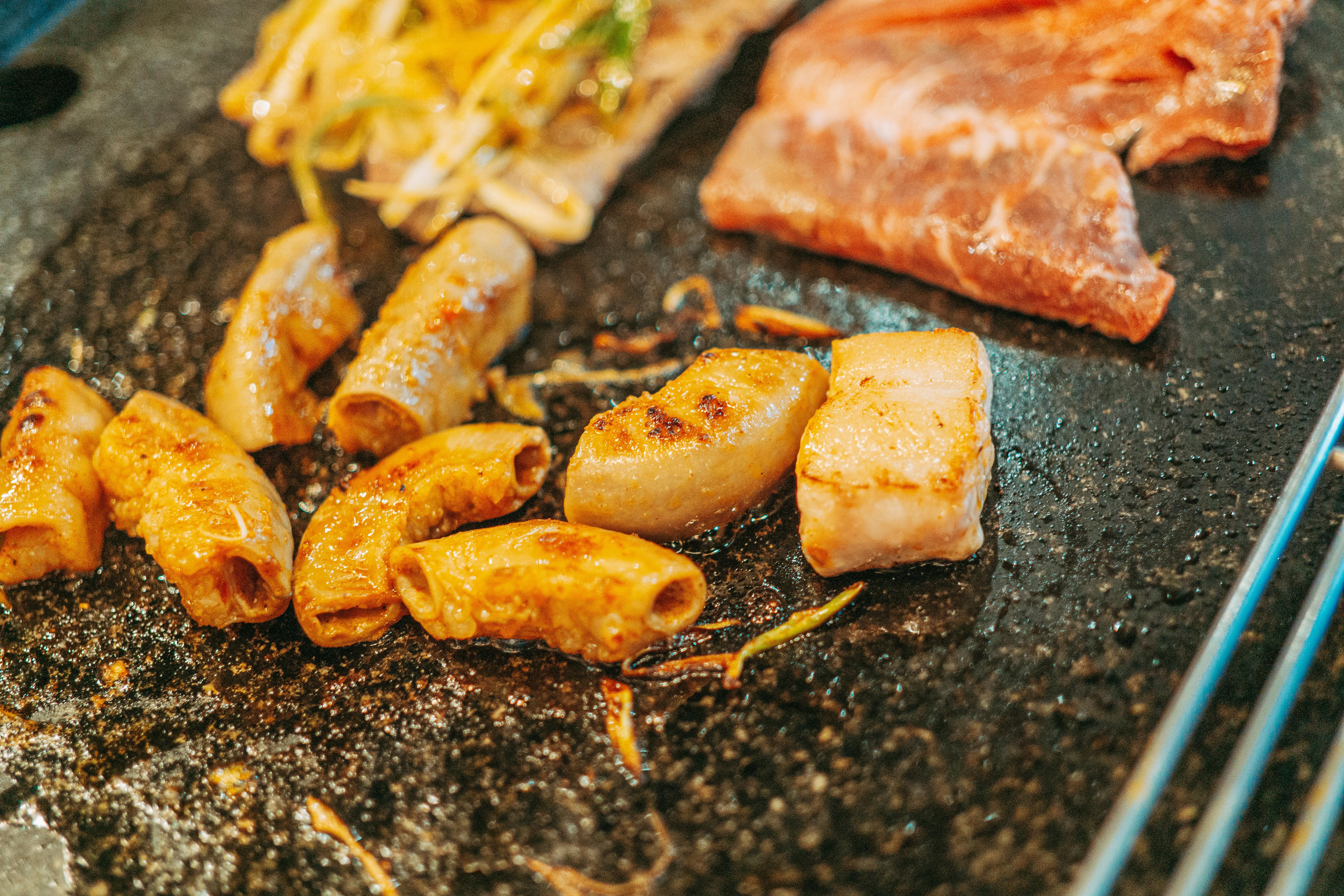 Close-up of grilled meat and intestines sizzling on a hot plate, ready to serve.