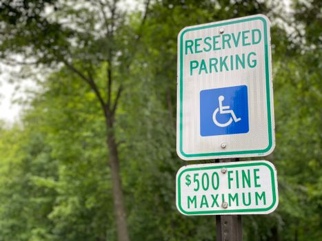 Close-up of a reserved parking sign with a fine notice, surrounded by lush greenery.