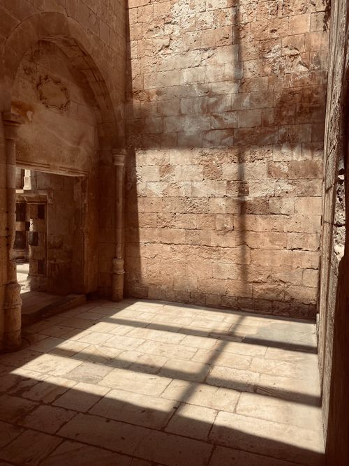 Free Historic stone interior with sunlight casting cross shadows on the floor, highlighting architectural beauty. Stock Photo