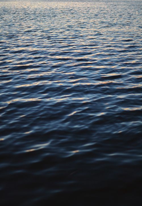 Free Close-up view of a calm ocean water surface reflecting sunset hues, perfect for backgrounds. Stock Photo