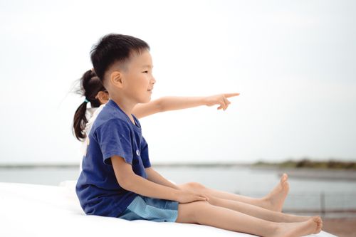 Free Two children enjoying a playful moment by the beach, pointing with excitement. Stock Photo