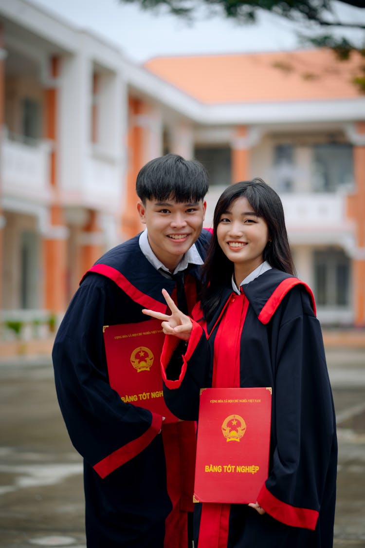 Boy And Girl Wearing Graduation Gowns