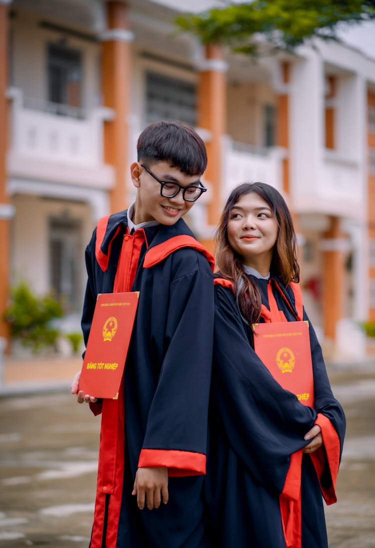 Boy And Girl Wearing Graduation Gowns