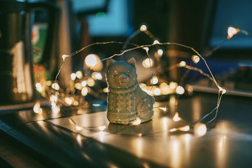 Foto De Primer Plano De Una Figura De Gato De Cerámica Gris Junto A Las Luces De Cadena