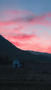 A lonely house in the secluded landscape of Fethiye, Turkey, under a vibrant dusk sky.