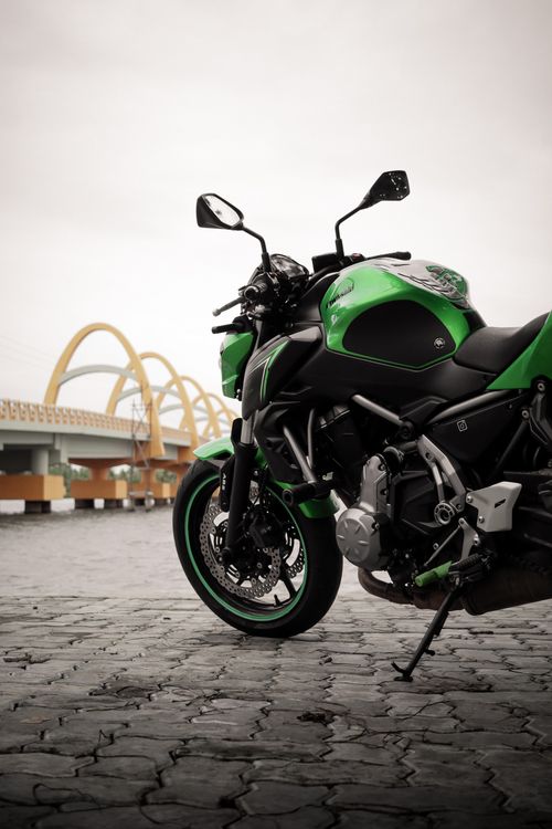 Free A vivid green sports bike parked outdoors with a bridge in the background. Stock Photo