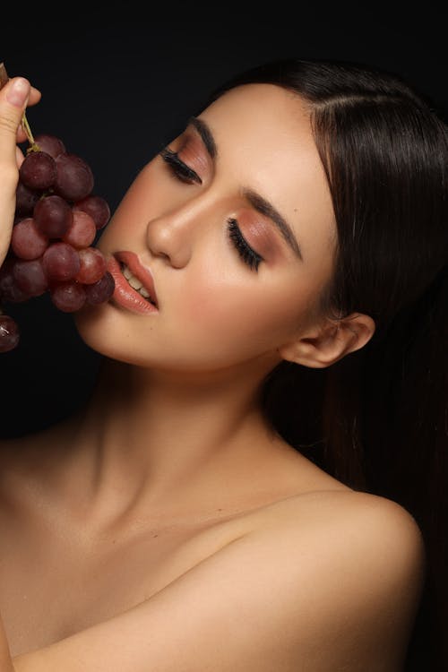 Naked Model with Grapes on Black Background