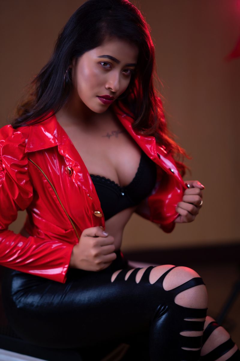 Fashion portrait of a woman in a striking red leather jacket and black attire. Modern and bold.