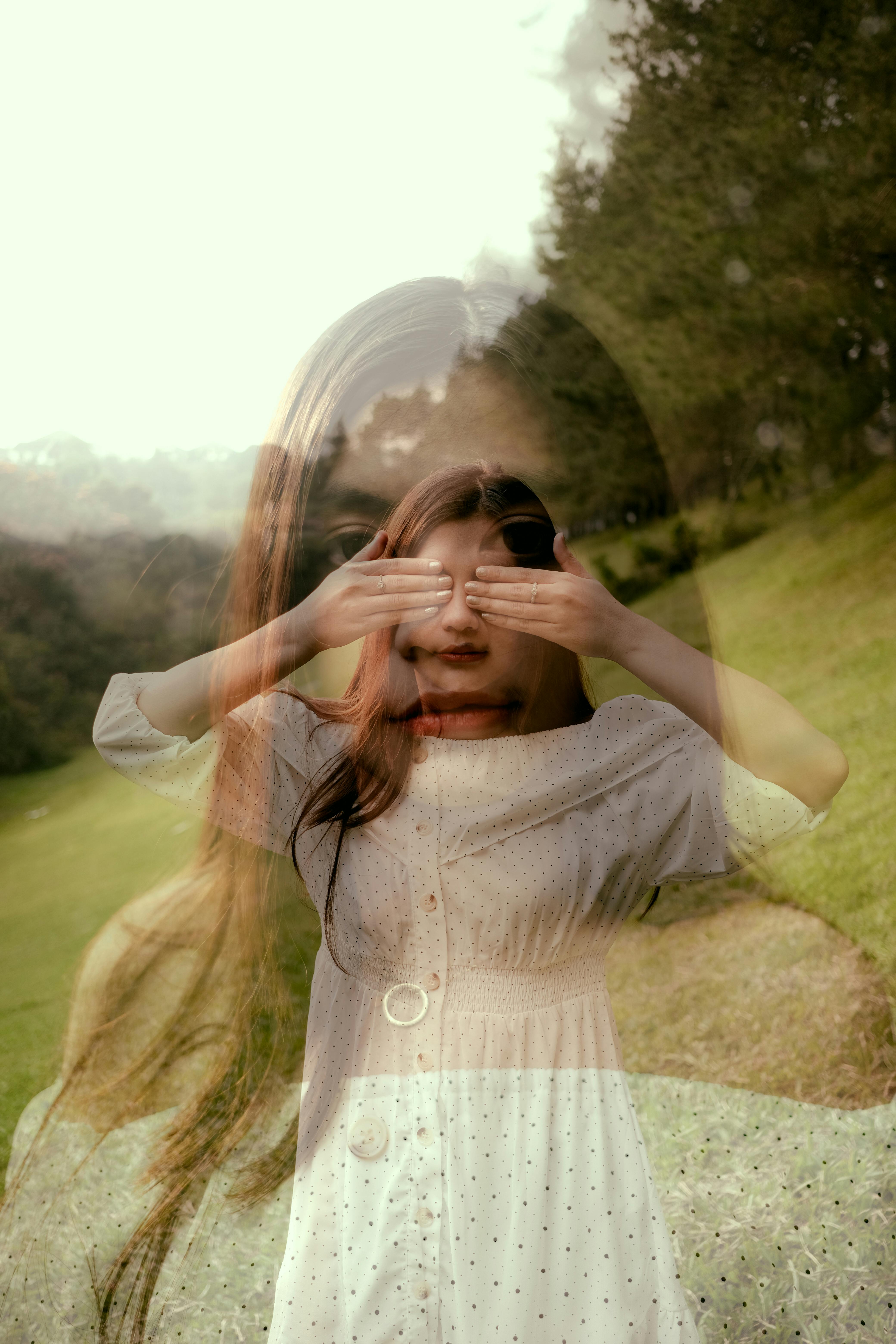 Artistic double exposure of a woman in nature, blending fashion and emotion.