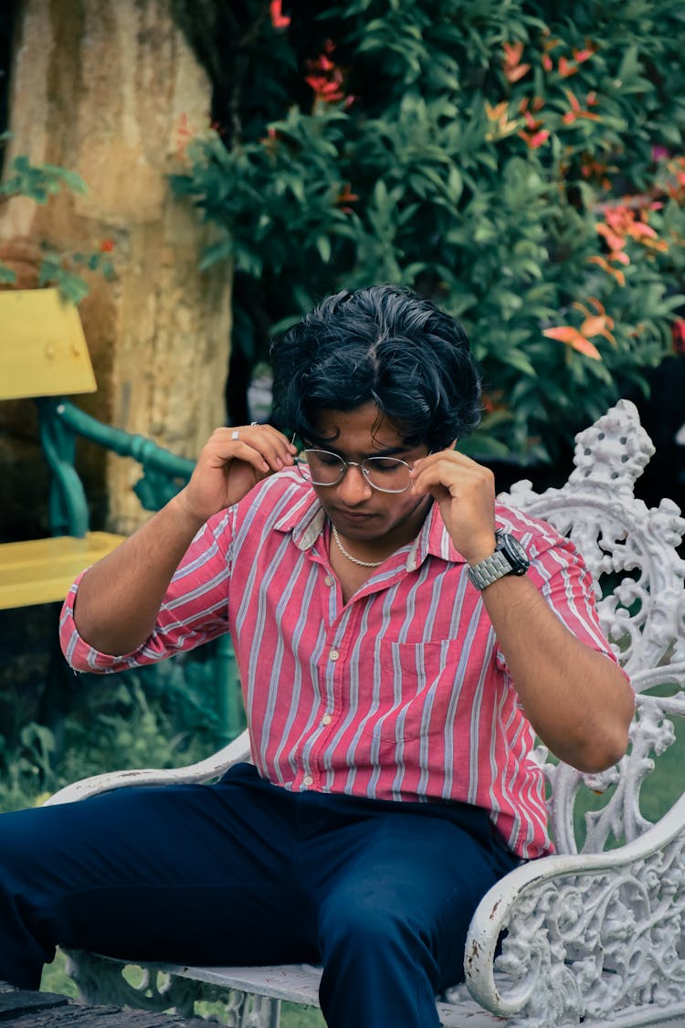 A Man In Striped Shirt Sitting On Chair In The Garden