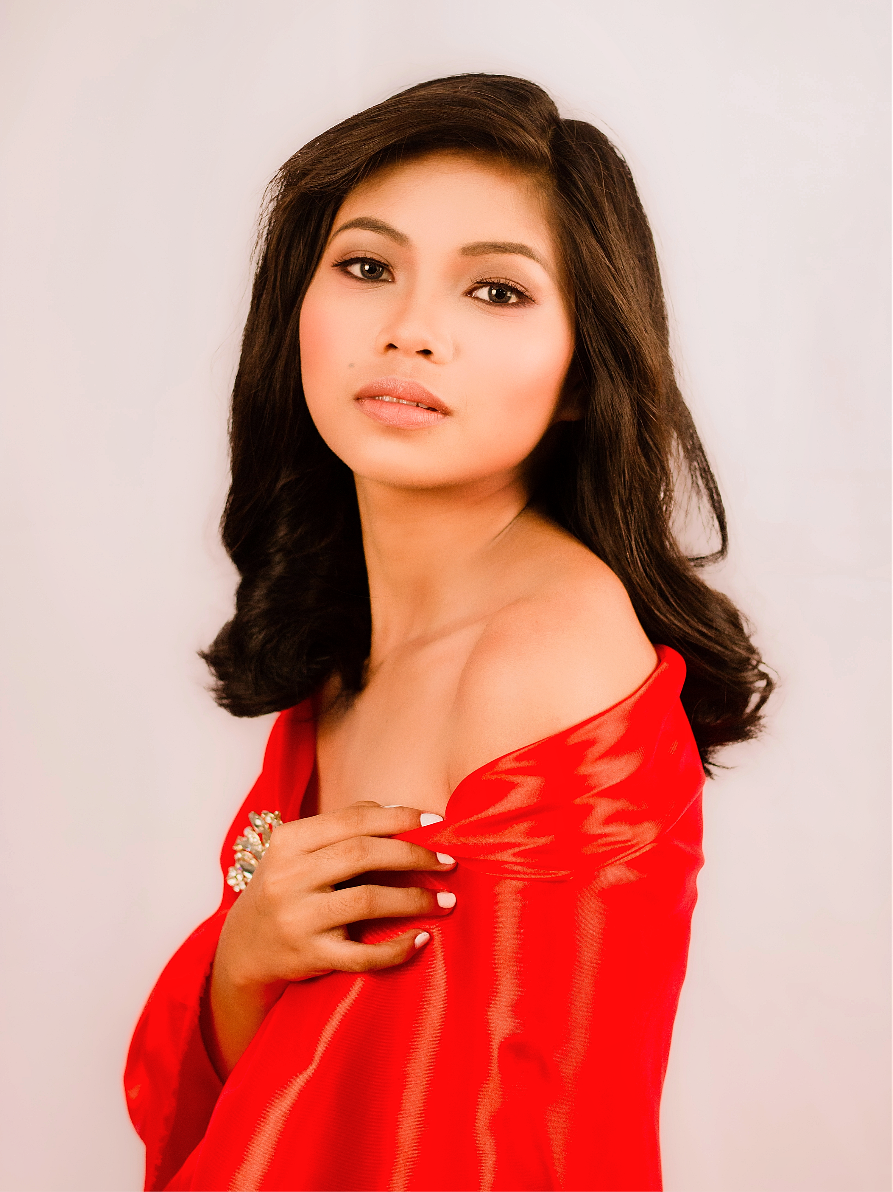 Beautiful woman wearing red dress, showcasing elegance and glamour in a studio setting.