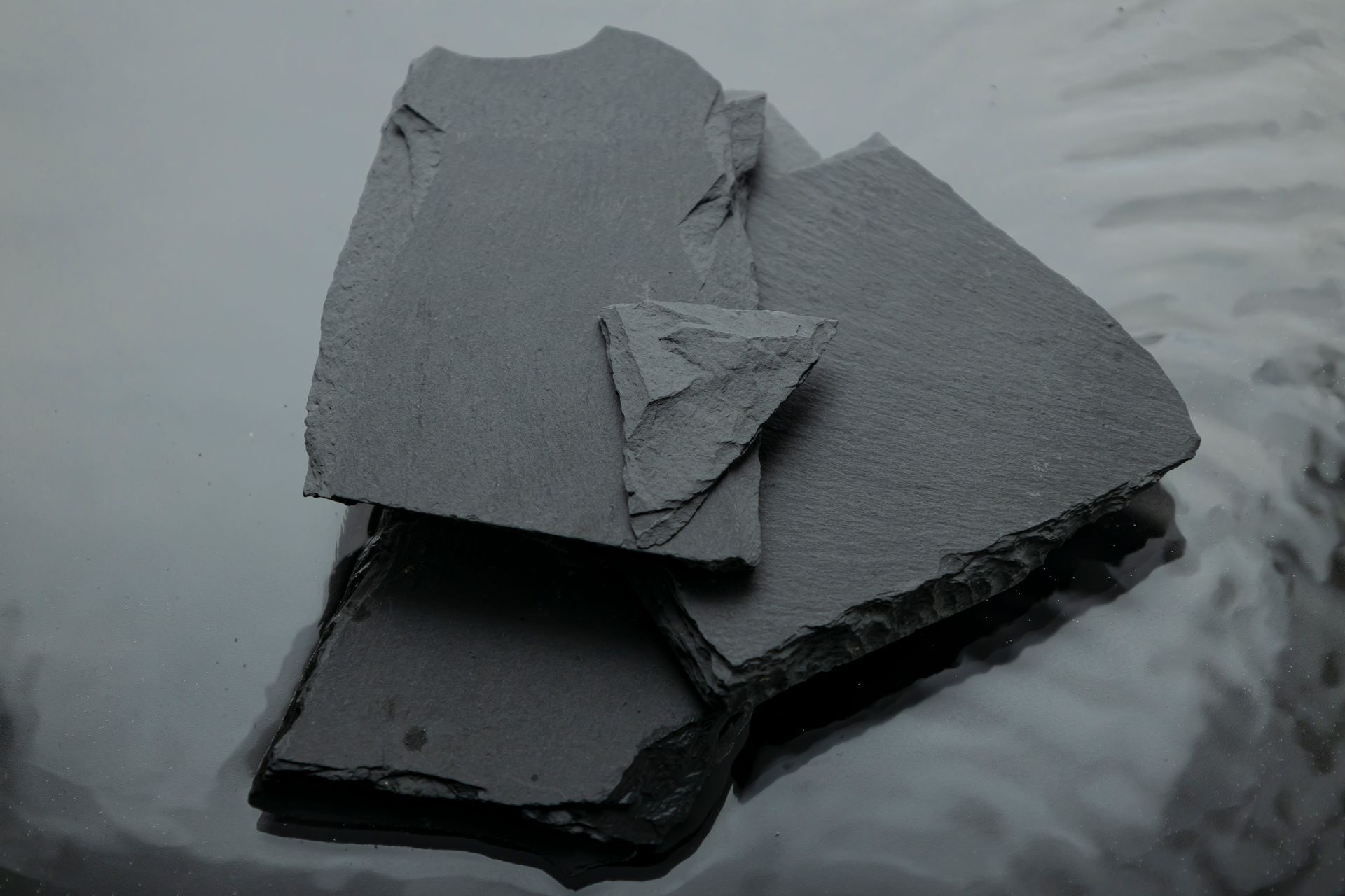 A close-up of gray slate rocks arranged in geometric shapes, offering a still life perspective.