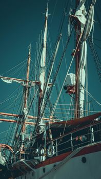 A stunning vertical close-up of a sailboat's masts and rigging against a clear blue sky.