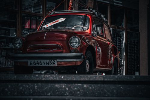 Free Classic vintage red car parked on a city street steps, showcasing retro automotive design. Stock Photo