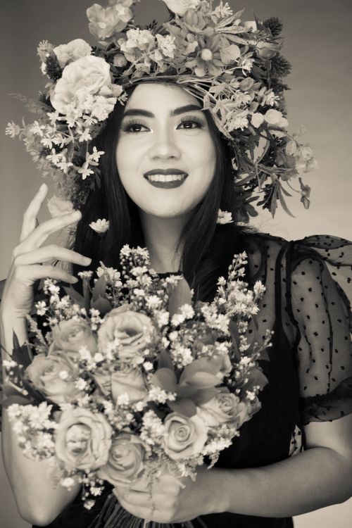 Free Sepia portrait of a smiling woman wearing a flower crown and holding roses. Stock Photo