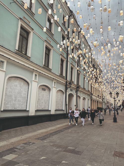 Photo of People Walking Under Hanging Lights