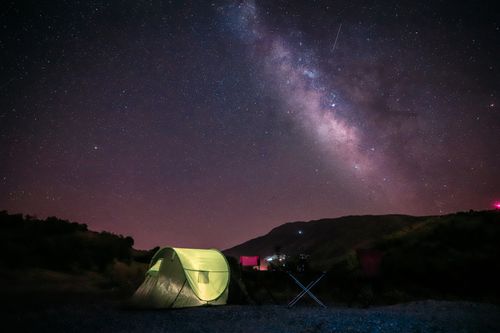 Free A serene camping scene under a vibrant Milky Way sky in a mountain landscape. Stock Photo