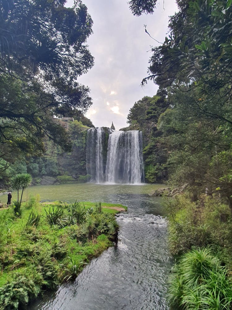 Waterfalls In The Middle Of Green Grass Trees