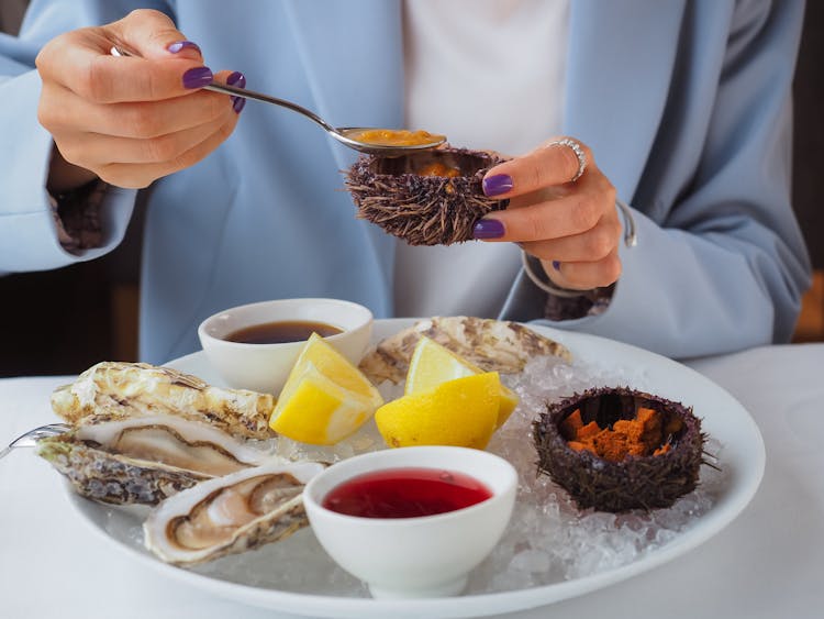 Close-up Of Woman Eating Oysters In Restaurant