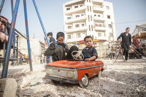Free Children enjoying playtime with a toy car in Idlib, Syria, showcasing innocence and joy. Stock Photo