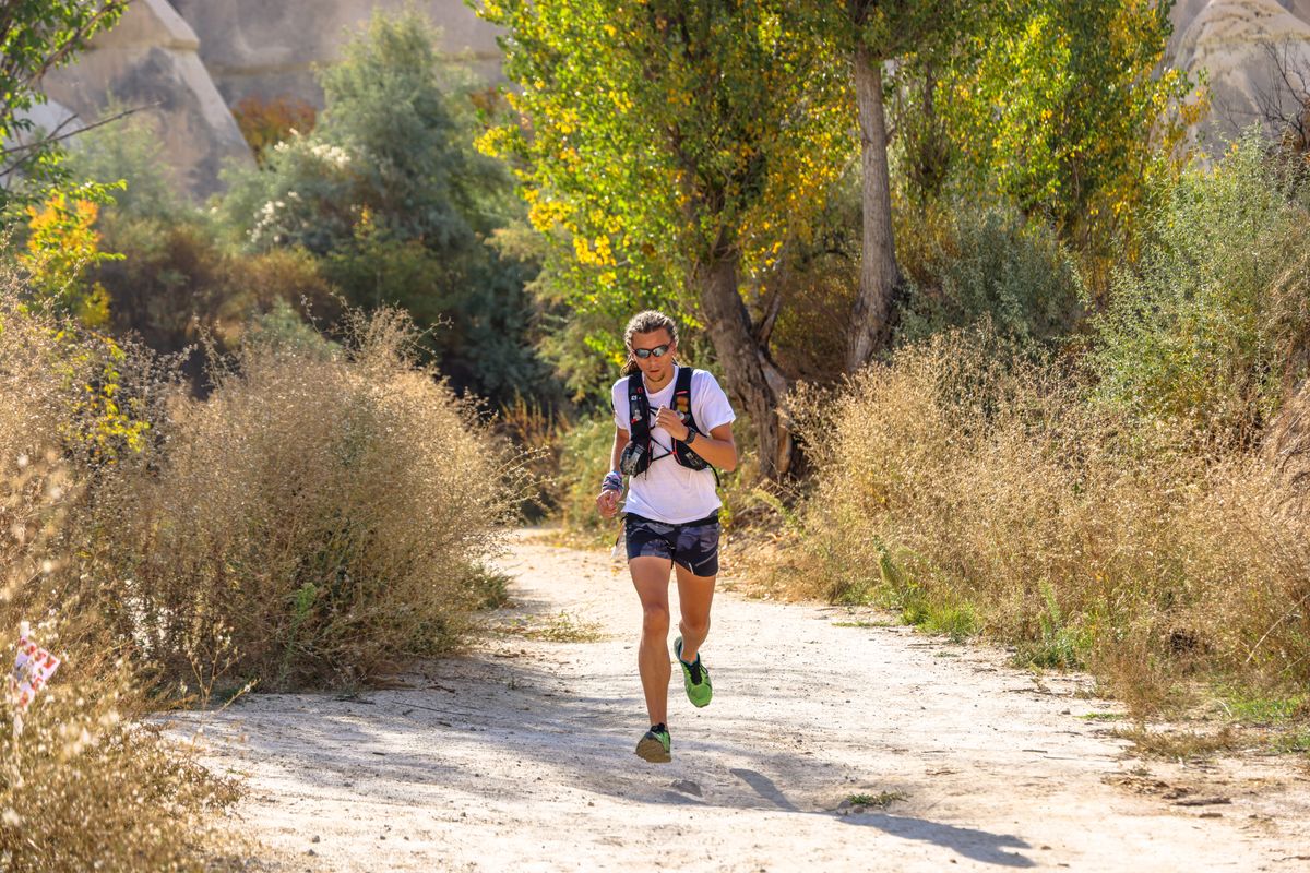 Runner in activewear moving along a scenic outdoor dirt trail