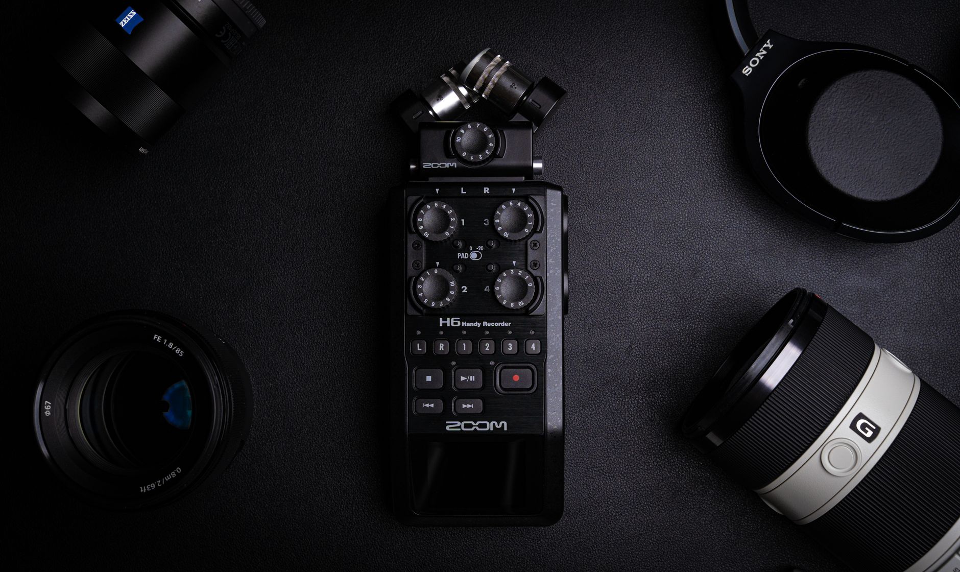 Top-down view of an audio recorder surrounded by camera gear on a black background. Ideal for media production themes.