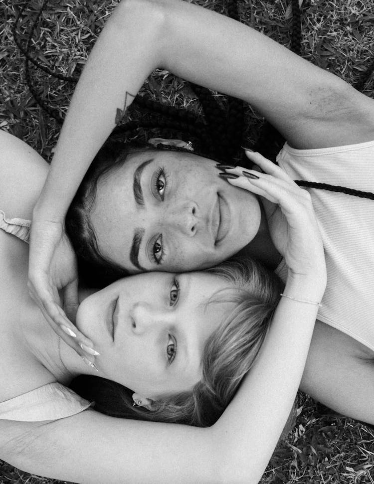 Portrait Of Women Lying On Ground Touching Heads