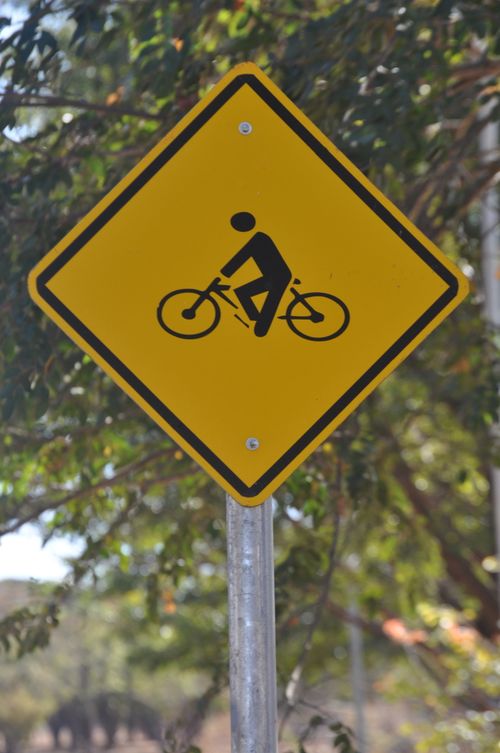 Free Yellow caution sign depicting a bicycle crossing warning on a sunny day. Stock Photo