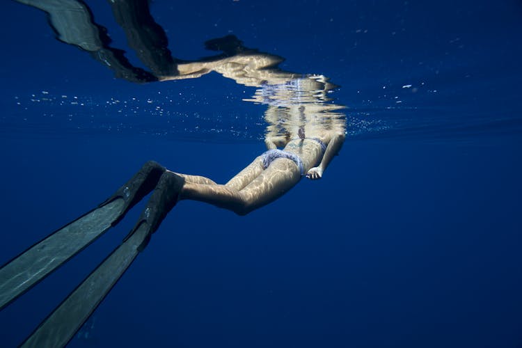 Woman In Diving Shoes Swimming Underwater