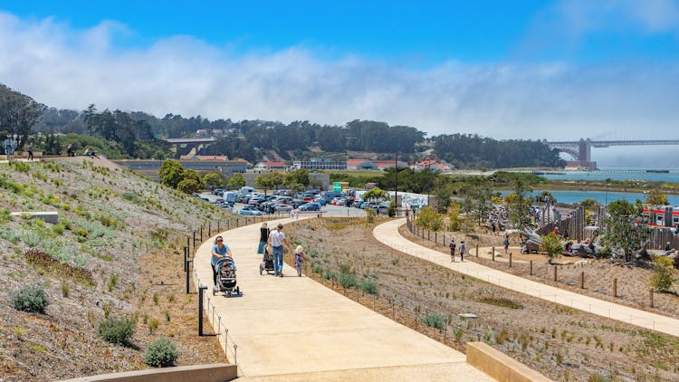 People With Strollers Walking On Path Near Sea