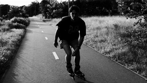 Free Man rollerblading on a sunny path in Vilnius, Lithuania, captured in black and white. Stock Photo