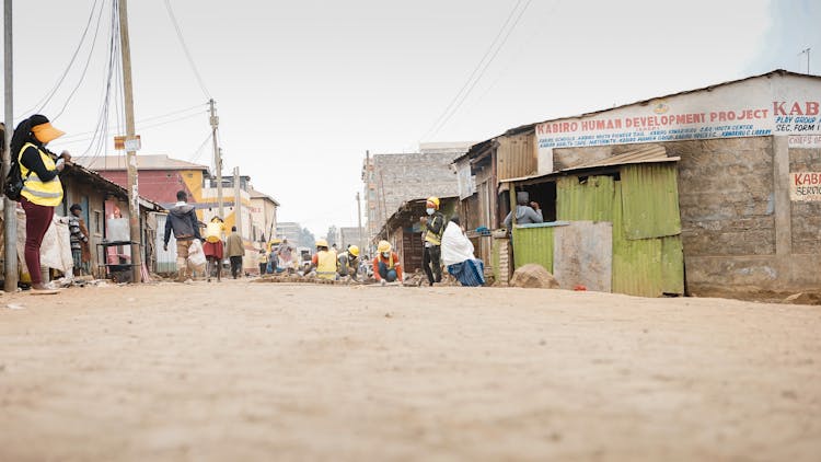 People Walking And Working On Dirt Road