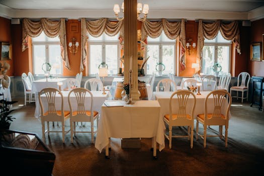 Luxurious dining room arranged with elegant chairs, tables, and classic curtains.