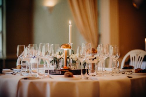 Free Sophisticated candlelit dinner table setup with wine glasses and floral centerpiece, perfect for elegant dining. Stock Photo