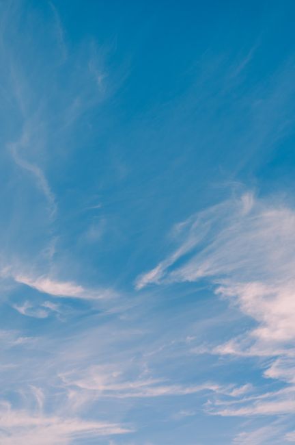 A tranquil skyscape featuring wispy clouds against a bright blue sky, ideal for backgrounds.