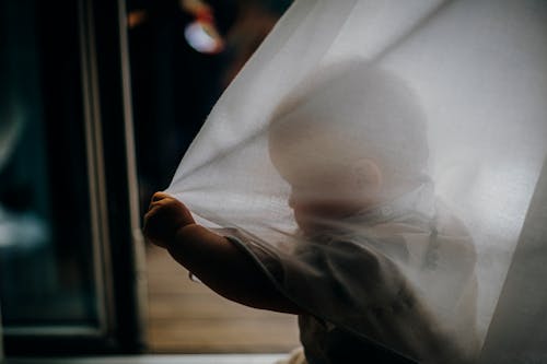 Free Baby Holding a White Curtain Stock Photo