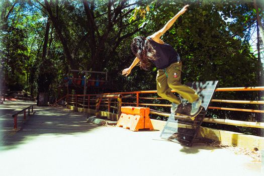 Man in Black T-shirt and Brown Pants Jumping on Orange and Black Metal Bar during