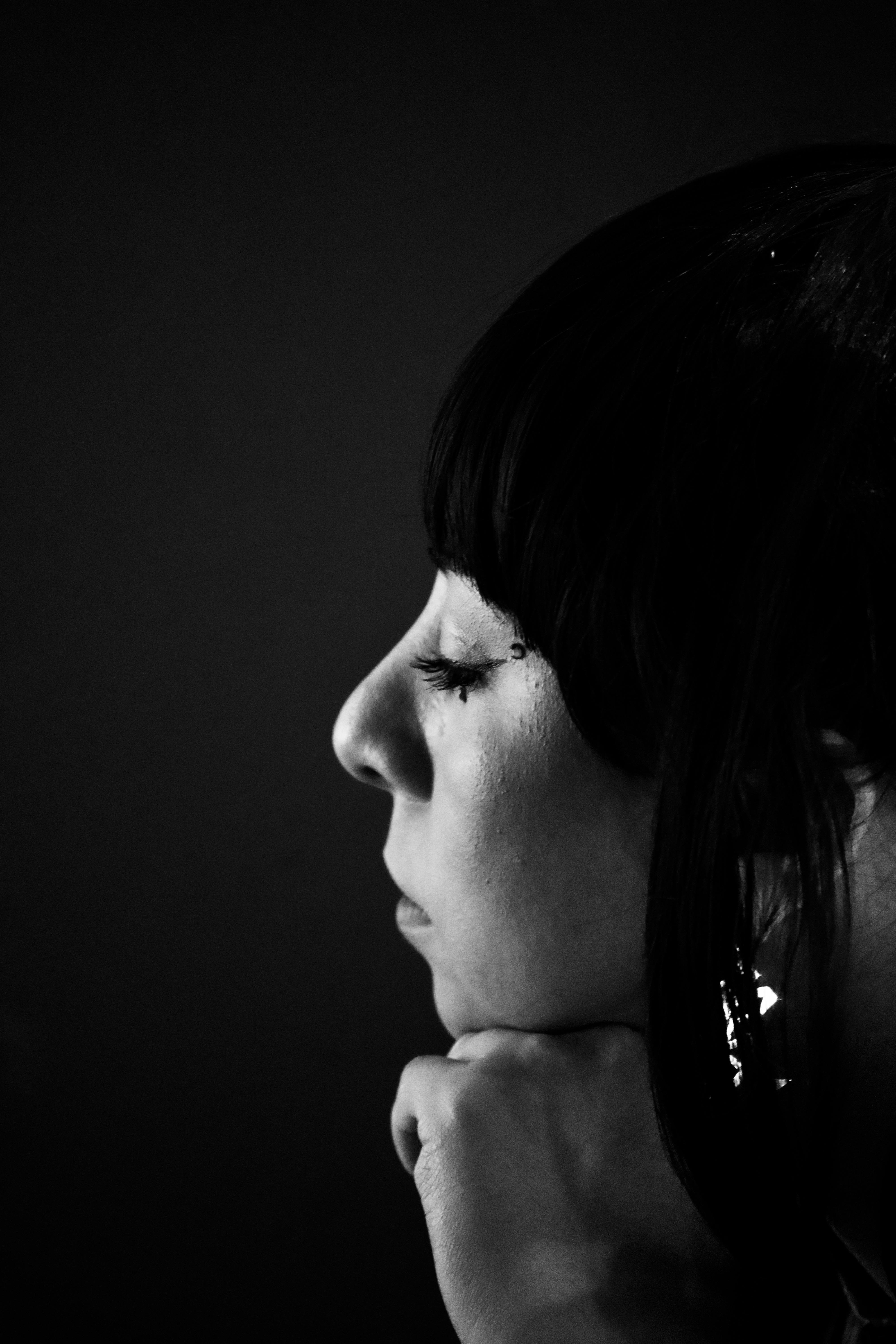 Black and white portrait of a woman with eyes closed and hand on chin.