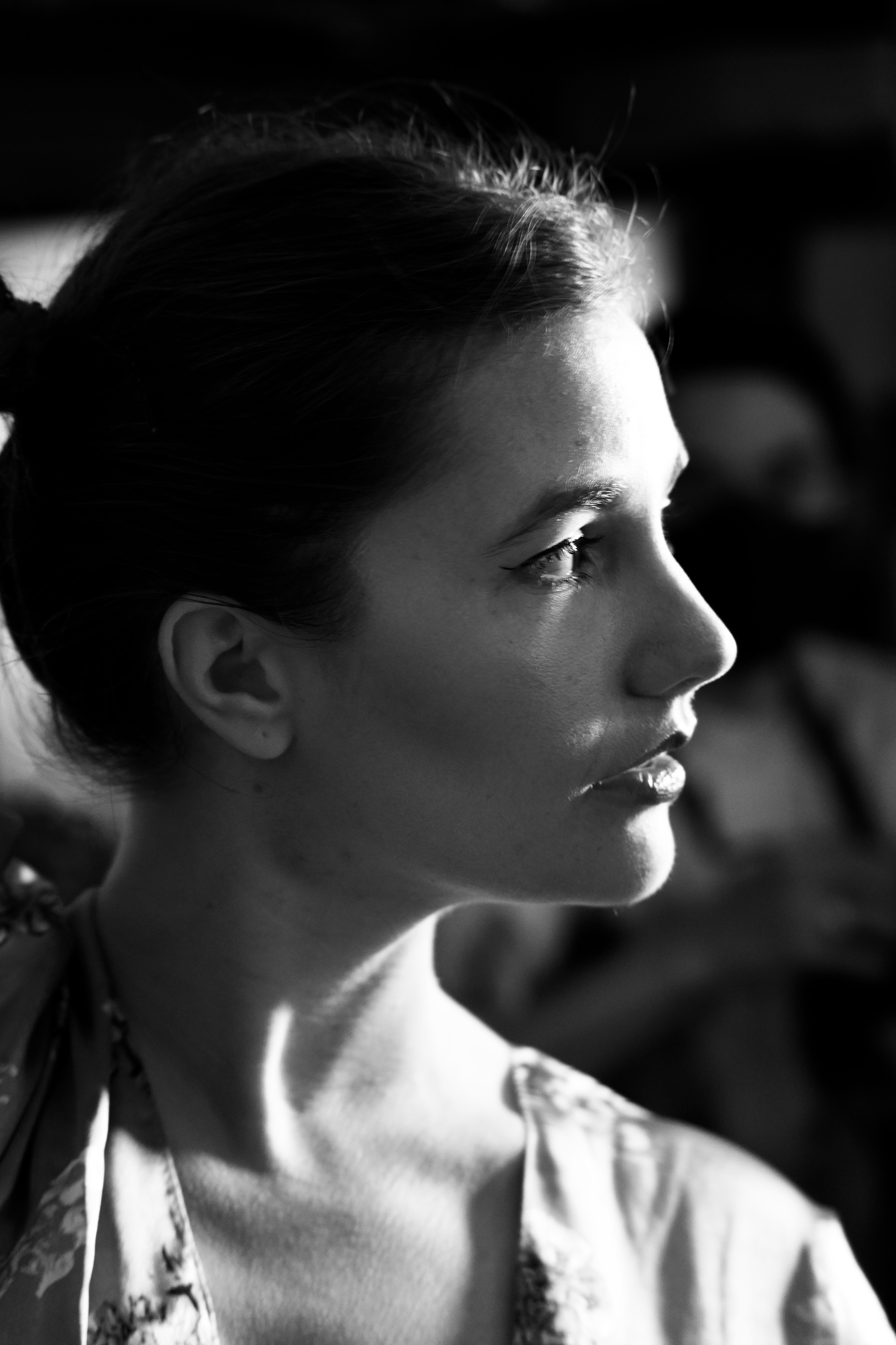 Black and white side profile of a woman in dramatic light, showcasing elegance.