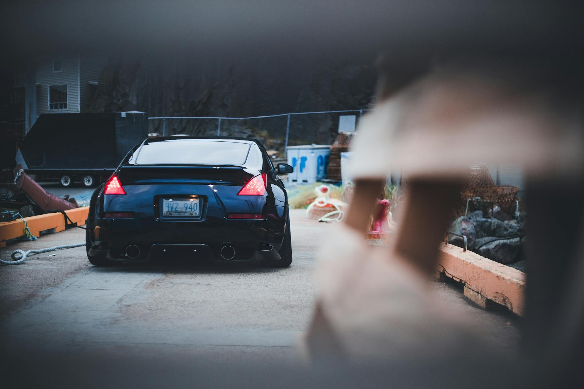 A sleek black Nissan 350Z parked outdoors, captured from the rear in an urban environment.