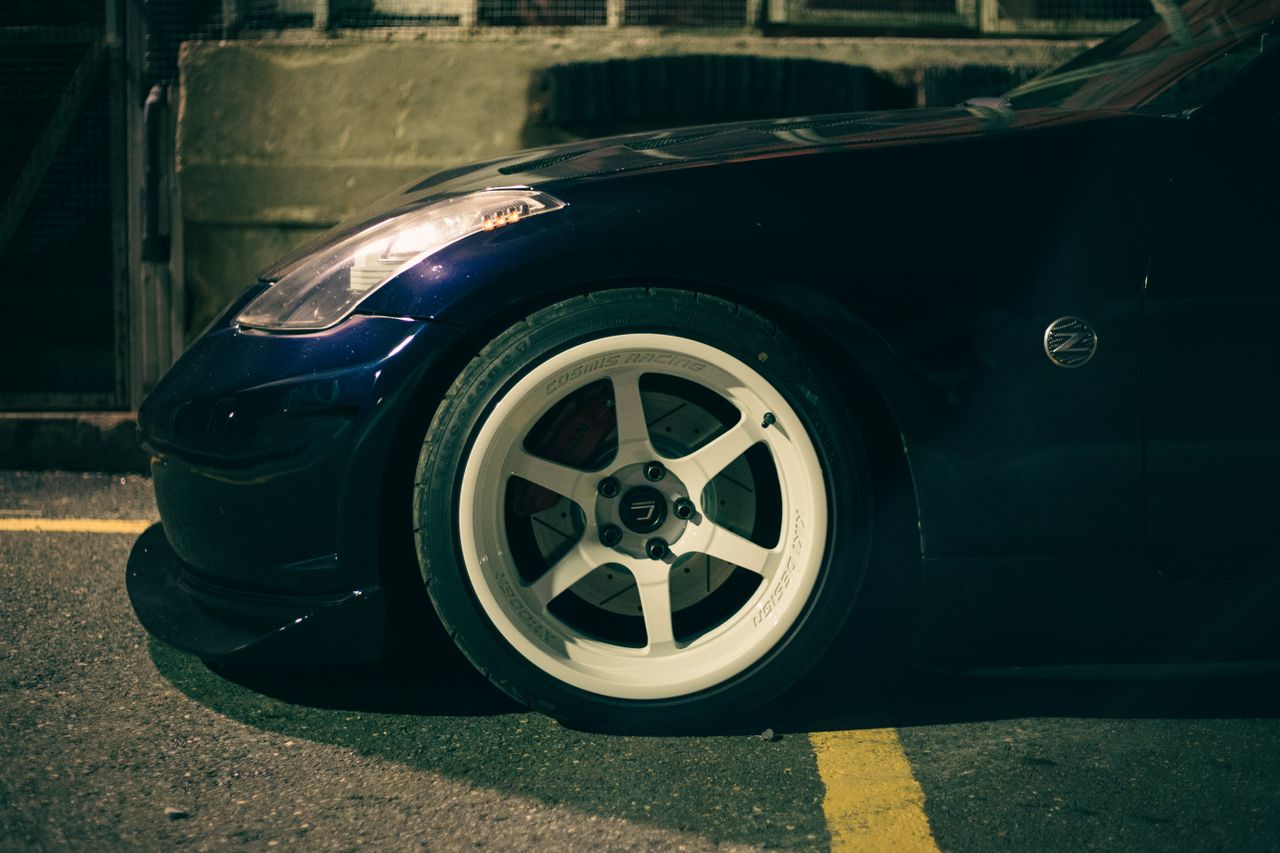side view close up of a nissan 350z sports car wheel parked on a stree