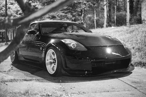 Grayscale Photography of Car Parked Near Grass