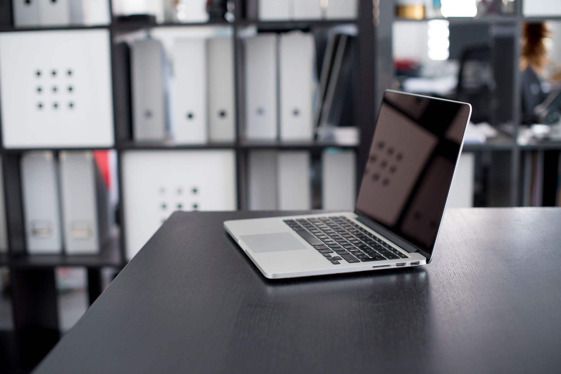 MacBook Pro displayed on a minimalist office desk with shelves in the background.