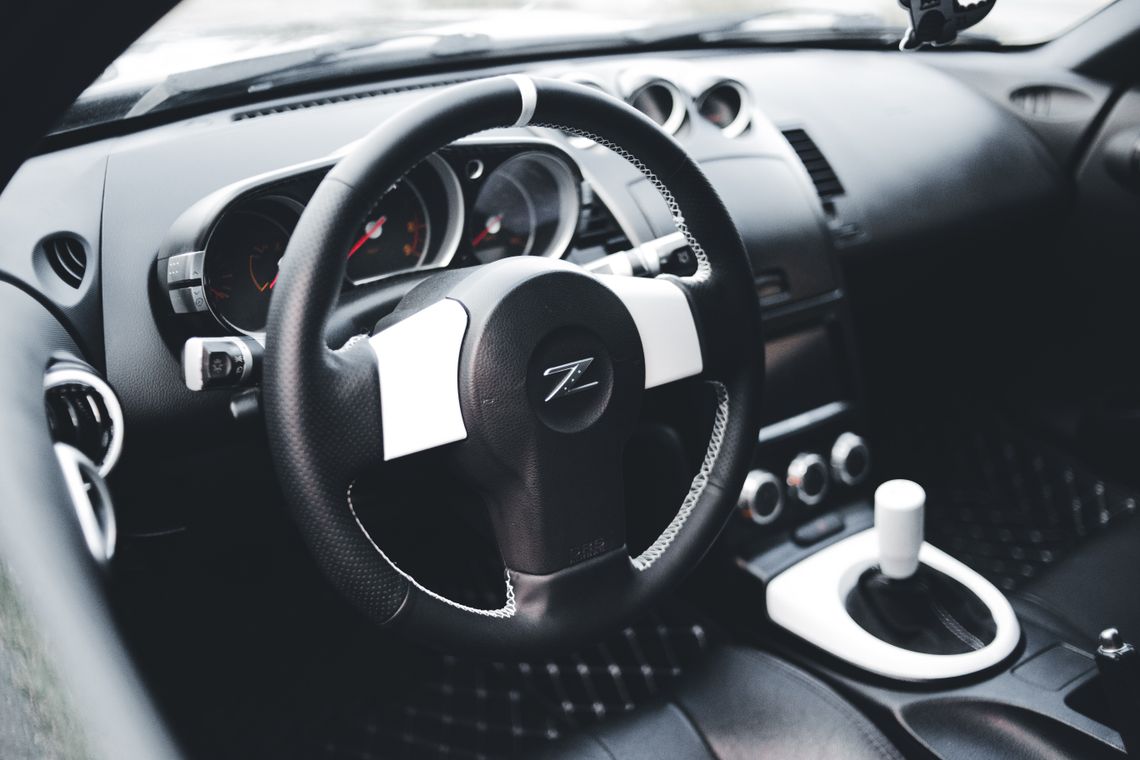 Real modern car interior with black steering wheel, center console and detailed driver environment
