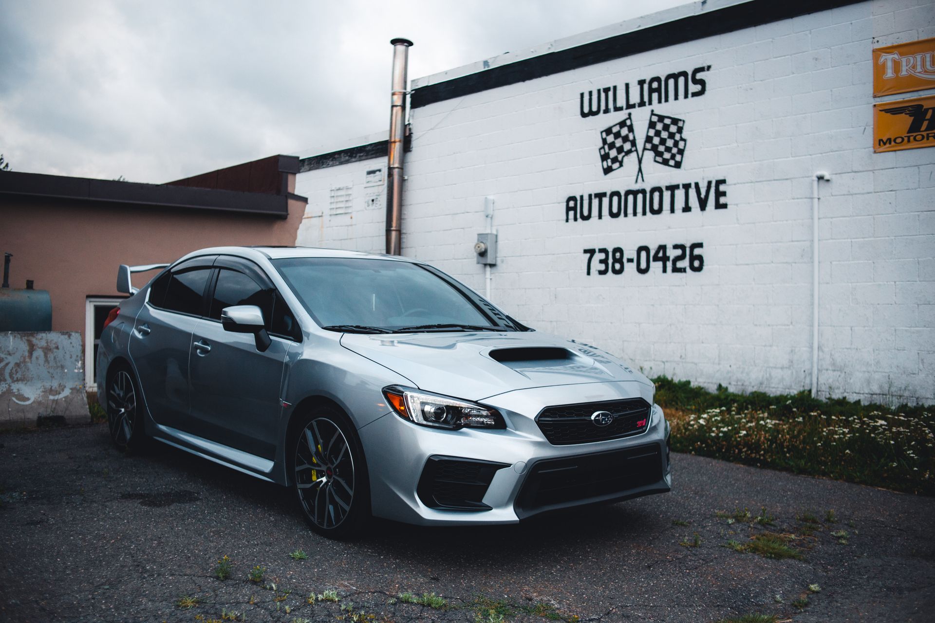 Sleek silver Subaru parked in an urban automotive lot with branding on building wall.